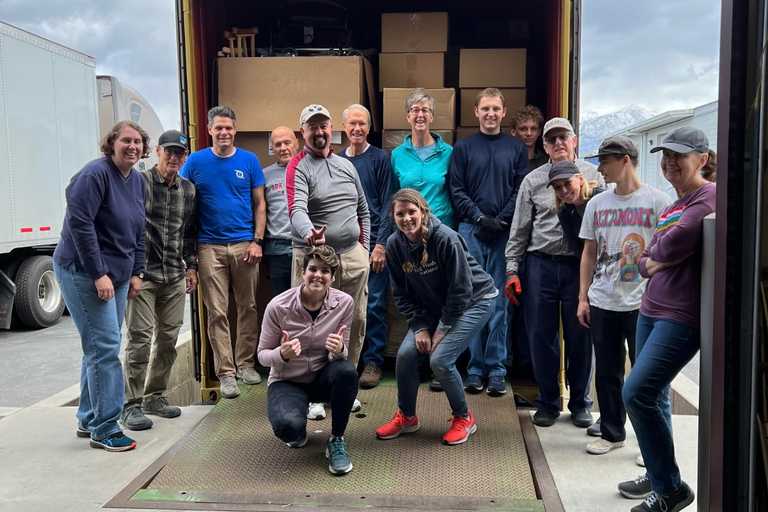 A team of volunteers posing next to a truck of donations they have loaded