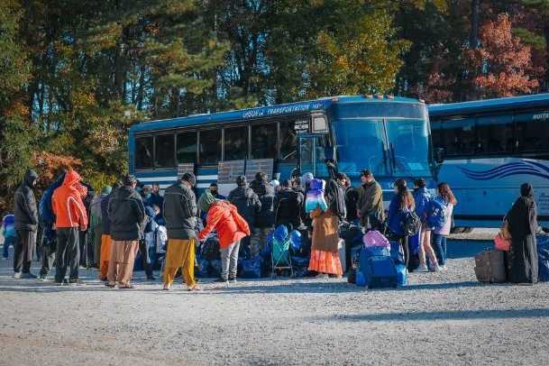 Individuals and children with luggage waiting to get on a bus