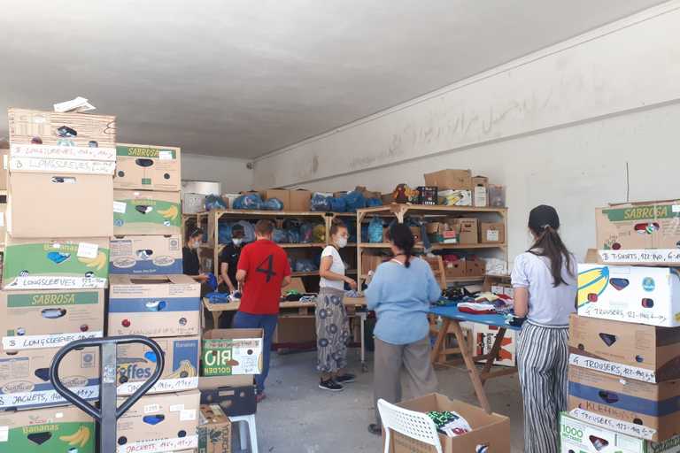 Volunteers sorting through donated clothes in a makeshift warehouse